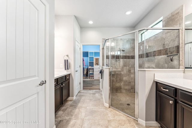 bathroom with vanity, recessed lighting, a spacious closet, and a shower stall