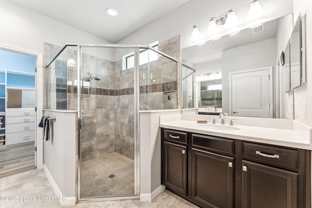 bathroom featuring visible vents, vanity, vaulted ceiling, and a shower stall