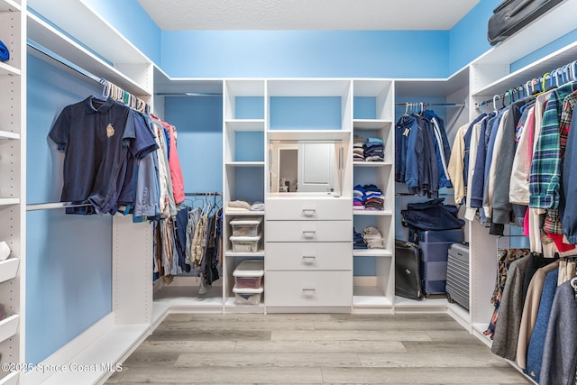 walk in closet with wood finished floors
