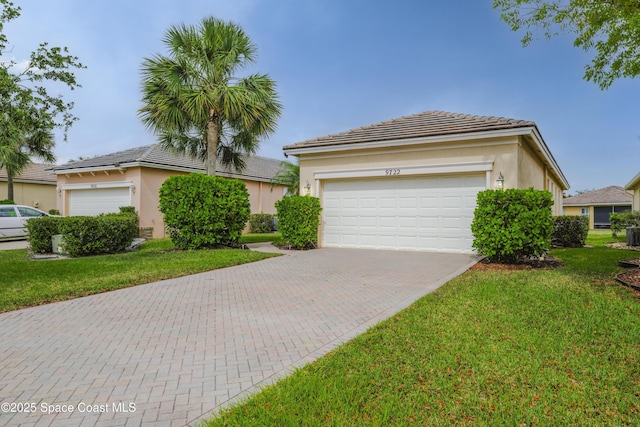 single story home featuring decorative driveway, a tile roof, a front lawn, and stucco siding