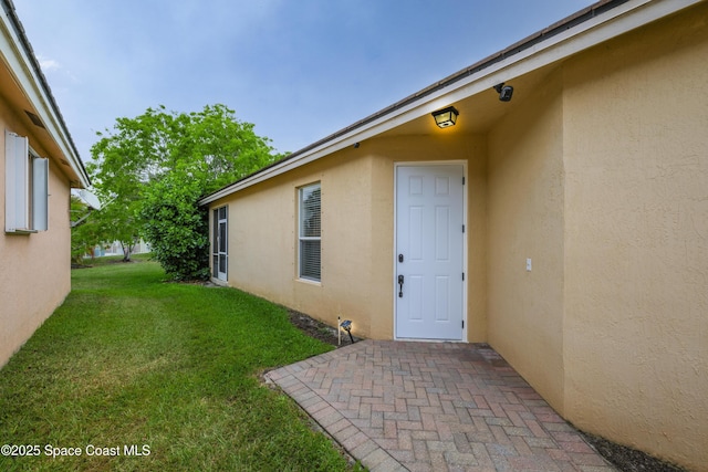 property entrance with stucco siding and a yard