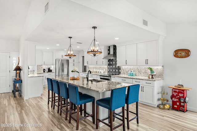 320 Amberjack Pl, Melbourne Beach, FL 32951 - kitchen featuring appliances with stainless steel finishes, a breakfast bar area, wall chimney exhaust hood, white cabinetry, and decorative backsplash