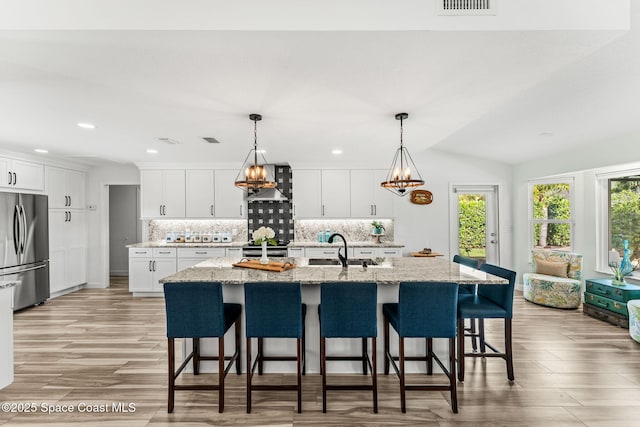 320 Amberjack Pl, Melbourne Beach, FL 32951 - kitchen featuring decorative backsplash, light wood-style floors, white cabinets, a sink, and appliances with stainless steel finishes