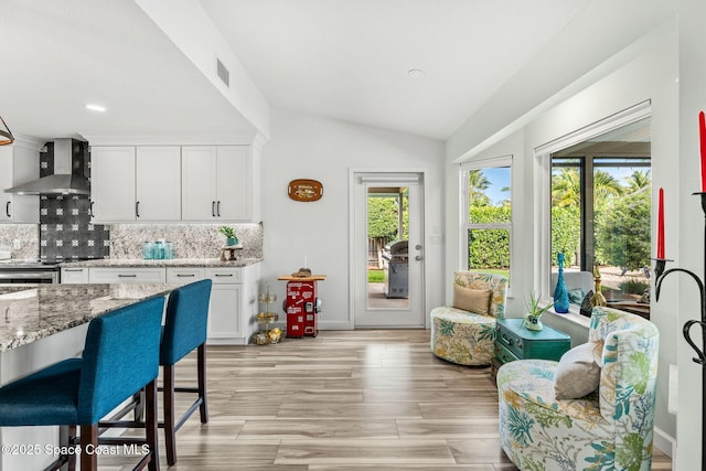 320 Amberjack Pl, Melbourne Beach, FL 32951 - kitchen with plenty of natural light, vaulted ceiling, wall chimney range hood, and tasteful backsplash