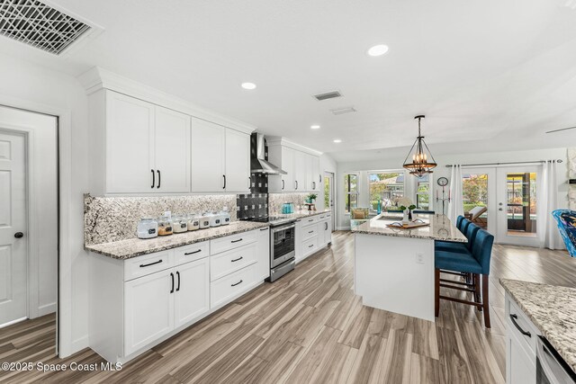 320 Amberjack Pl, Melbourne Beach, FL 32951 - kitchen featuring visible vents, wall chimney exhaust hood, stainless steel electric stove, and french doors