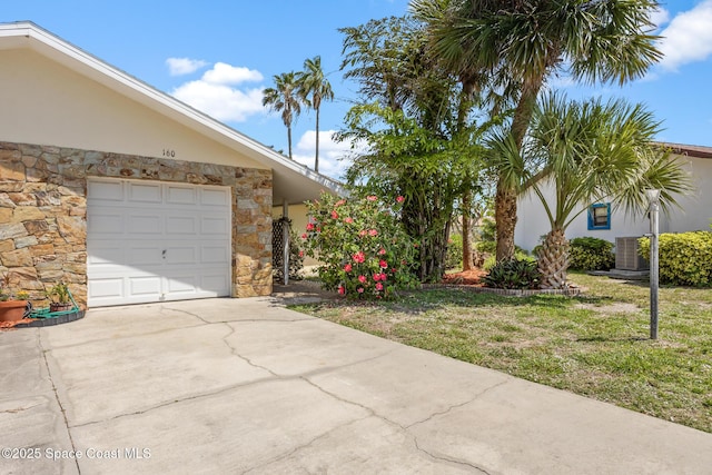 view of side of property with concrete driveway, central air condition unit, stone siding, and stucco siding