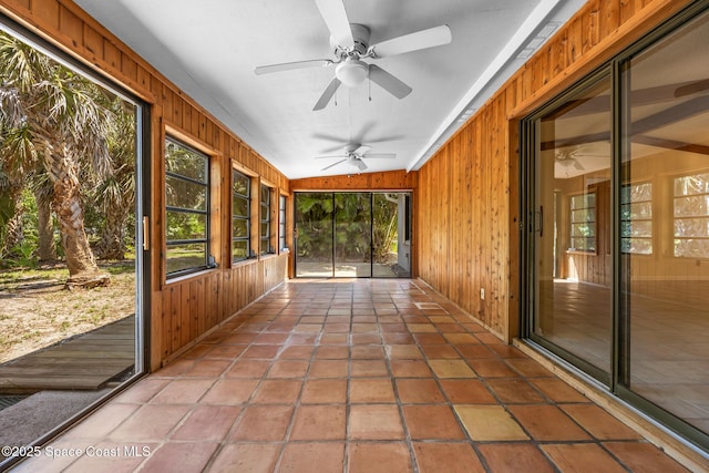 unfurnished sunroom featuring a ceiling fan and plenty of natural light