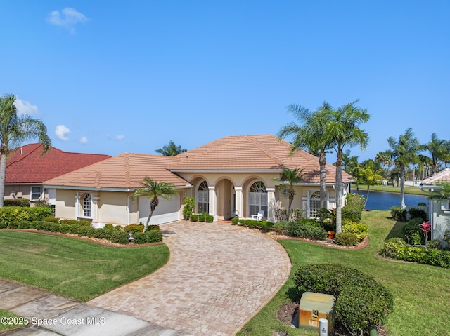 mediterranean / spanish-style house featuring stucco siding, decorative driveway, and a front lawn