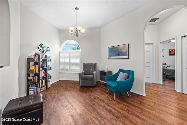 living area featuring wood finished floors, arched walkways, a chandelier, baseboards, and visible vents