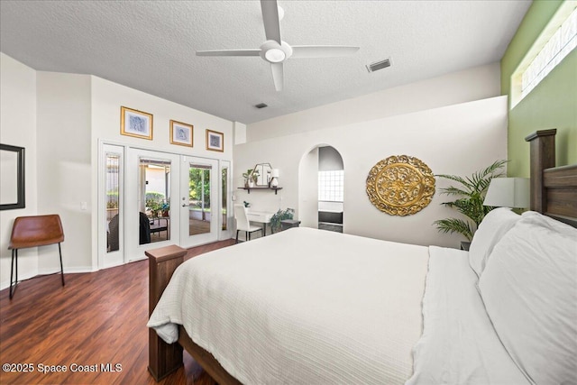bedroom featuring wood finished floors, access to exterior, a textured ceiling, arched walkways, and french doors