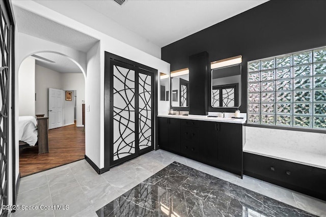 bathroom featuring double vanity, baseboards, and ensuite bathroom