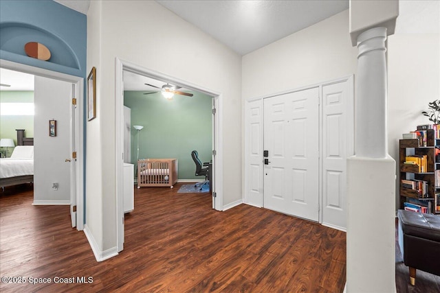 entrance foyer featuring baseboards, ornate columns, ceiling fan, and dark wood-type flooring