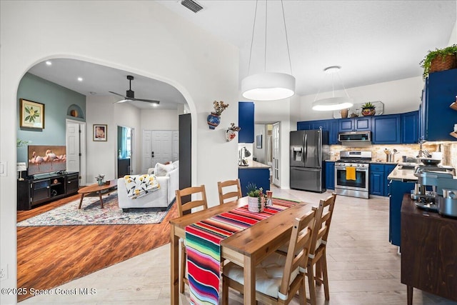dining space with light wood-style flooring, visible vents, ceiling fan, arched walkways, and recessed lighting