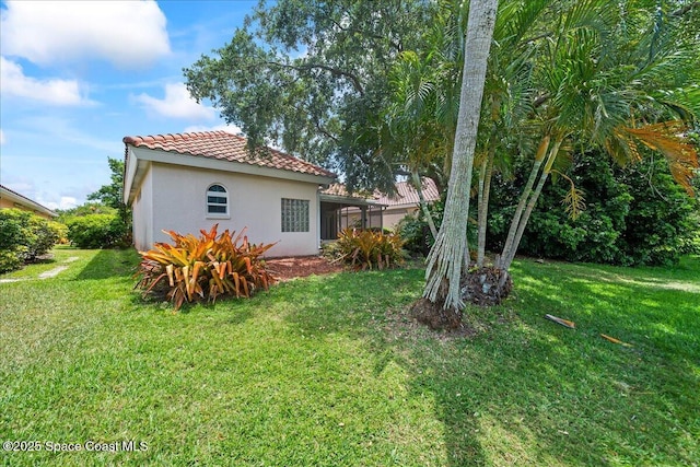 back of property featuring stucco siding, a yard, and a tiled roof