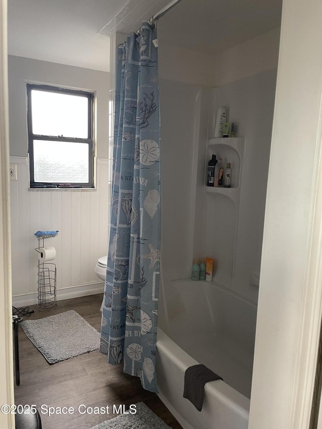 bathroom featuring wainscoting, toilet, wood finished floors, and shower / bath combination with curtain