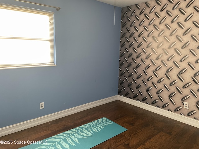 spare room with baseboards and dark wood finished floors