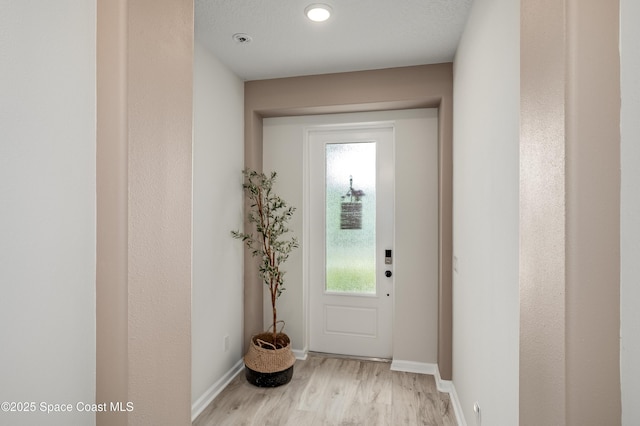 doorway with baseboards and light wood-style flooring