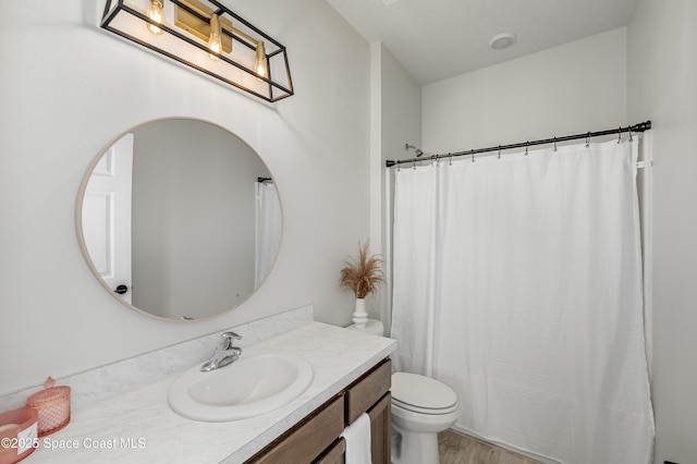 bathroom with wood finished floors, toilet, curtained shower, and vanity