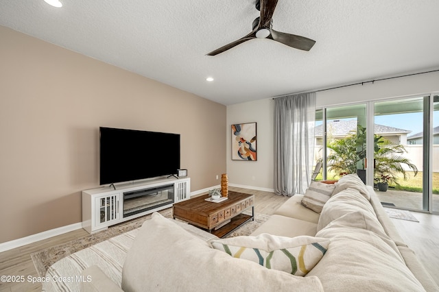 living room with a ceiling fan, a textured ceiling, baseboards, light wood-style floors, and recessed lighting