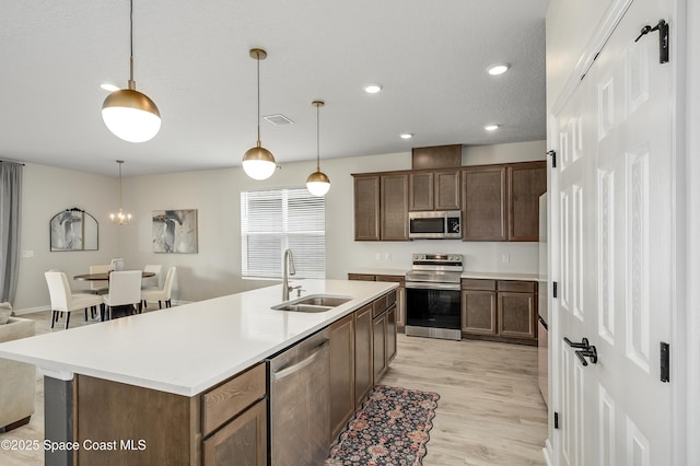kitchen featuring a sink, appliances with stainless steel finishes, light wood-style flooring, and light countertops
