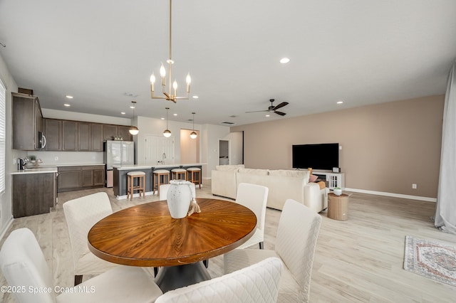 dining space with recessed lighting, baseboards, light wood-style flooring, and ceiling fan with notable chandelier