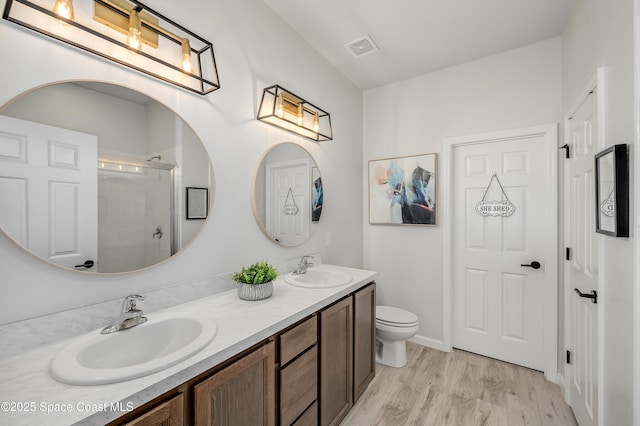 bathroom featuring visible vents, a sink, a shower with door, and wood finished floors