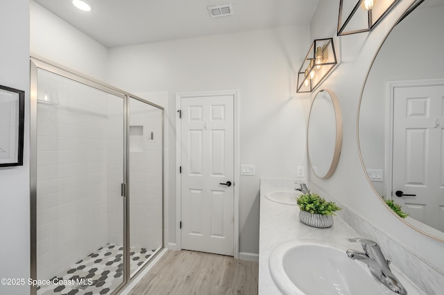 full bathroom featuring a sink, a stall shower, wood finished floors, and visible vents