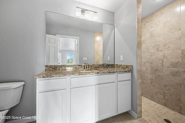 bathroom featuring vanity, toilet, and tiled shower