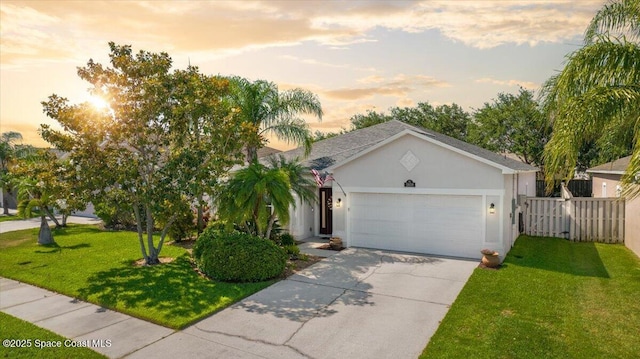 view of front of property with driveway, fence, a front yard, stucco siding, and a garage