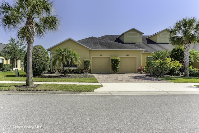 6008 Van Ness Dr, Melbourne, FL 32940 - view of front of property featuring a garage, decorative driveway, a front lawn, a shingled roof, and stucco siding