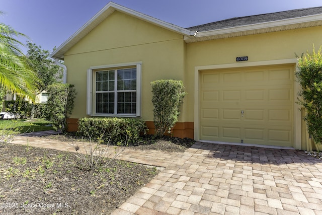 6008 Van Ness Dr, Melbourne, FL 32940 - exterior space featuring a garage, stucco siding, and decorative driveway