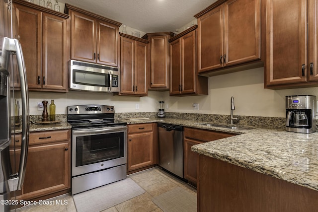 6008 Van Ness Dr, Melbourne, FL 32940 - kitchen with a textured ceiling, a sink, light tile patterned floors, stone countertops, and stainless steel appliances