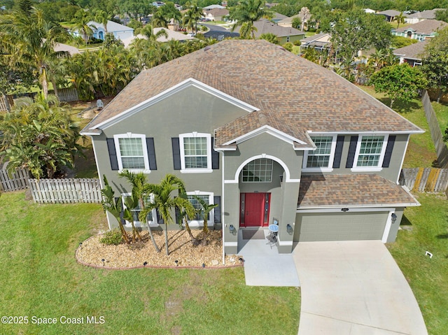 traditional-style home with stucco siding, fence, driveway, and a front lawn