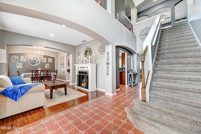 living room with recessed lighting, arched walkways, a chandelier, baseboards, and stairway