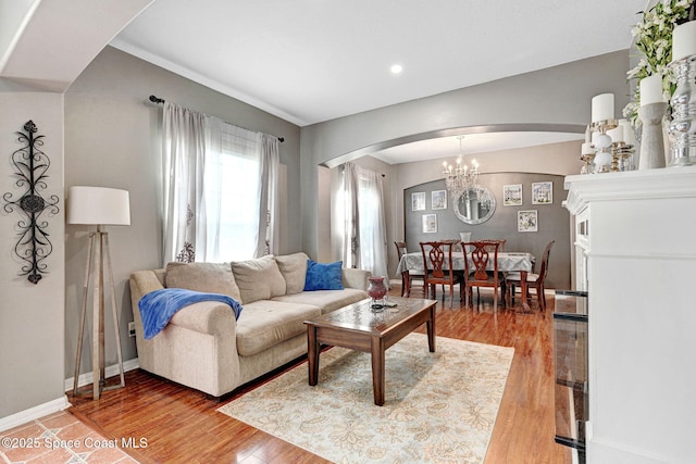 living area featuring recessed lighting, arched walkways, baseboards, and light wood-type flooring