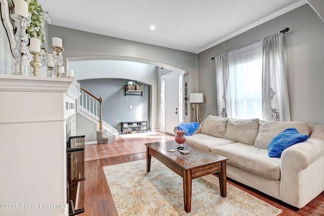 living area with recessed lighting, arched walkways, stairs, and wood finished floors