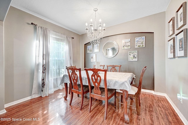 dining space with wood finished floors, a notable chandelier, and baseboards