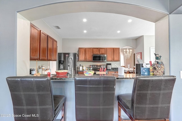 kitchen featuring recessed lighting, stainless steel appliances, a peninsula, and arched walkways