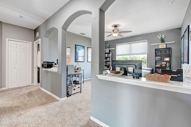 kitchen with ceiling fan, visible vents, baseboards, arched walkways, and carpet