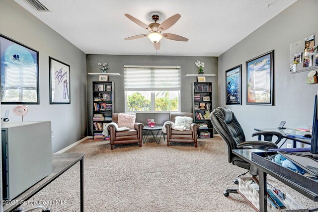 office space with visible vents, a ceiling fan, and carpet