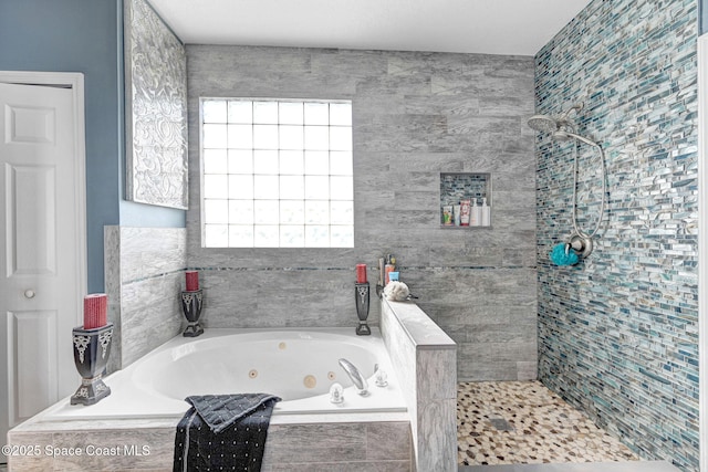 bathroom featuring a tub with jets and a tile shower