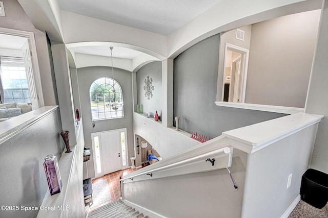 foyer with arched walkways, visible vents, and baseboards