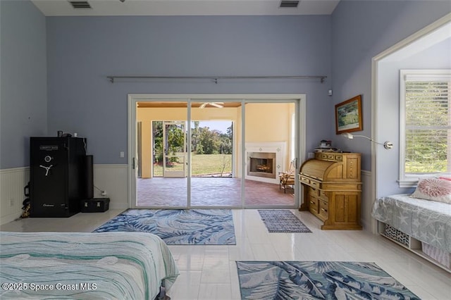 bedroom with light tile patterned flooring, visible vents, access to exterior, and wainscoting