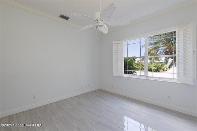 empty room featuring light wood-style flooring, ornamental molding, baseboards, visible vents, and a ceiling fan