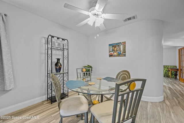 dining area featuring visible vents, baseboards, ceiling fan, and light wood-type flooring