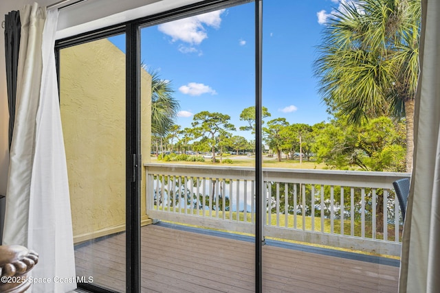 doorway to outside featuring baseboards, a water view, a textured wall, and a wealth of natural light