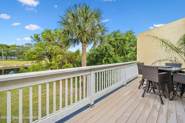 deck with outdoor dining area and a yard