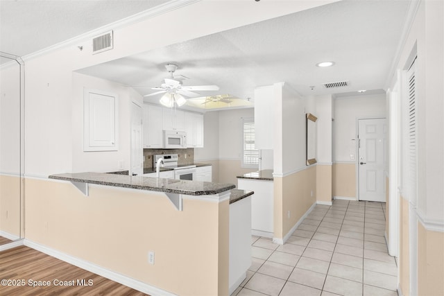 104 Riverside Dr Unit 402, Cocoa, FL 32922 - kitchen with white appliances, a peninsula, visible vents, and a breakfast bar