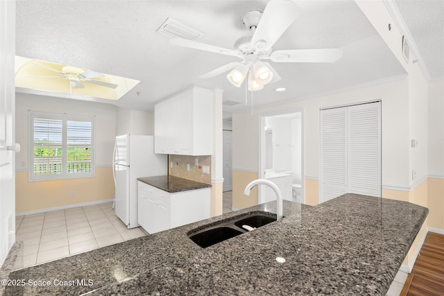 104 Riverside Dr Unit 402, Cocoa, FL 32922 - kitchen with ceiling fan, a sink, freestanding refrigerator, white cabinetry, and baseboards