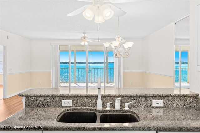 104 Riverside Dr Unit 402, Cocoa, FL 32922 - kitchen featuring wood finished floors, stone countertops, a water view, a sink, and ceiling fan with notable chandelier